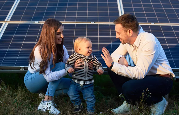 Parents smiling at toddler in front of solar panels