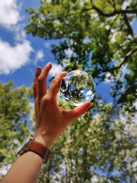 Person holding a glass globe against the sky to represent sustainable energy solutions