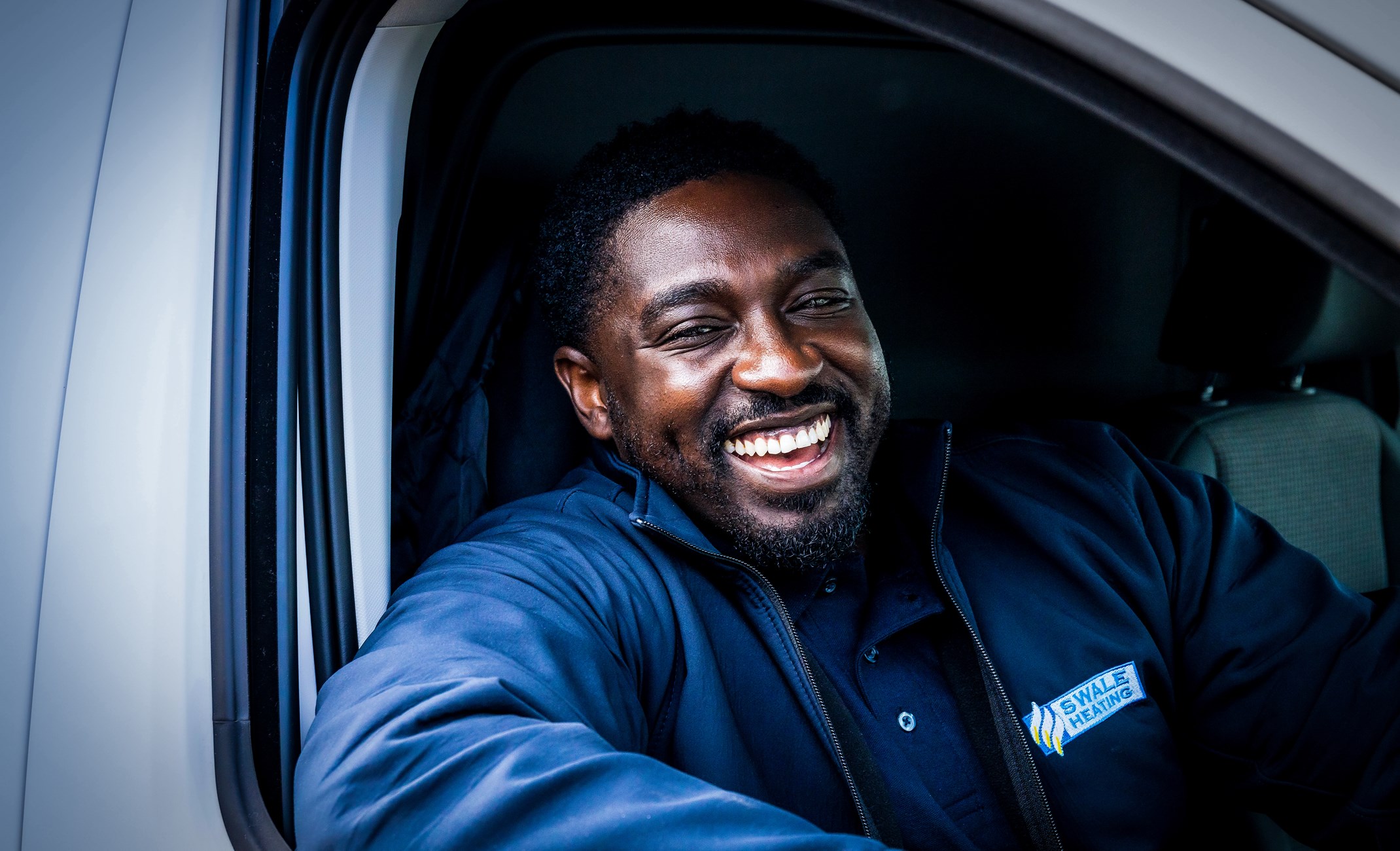 Man in Swale Heating uniform smiling out of car window