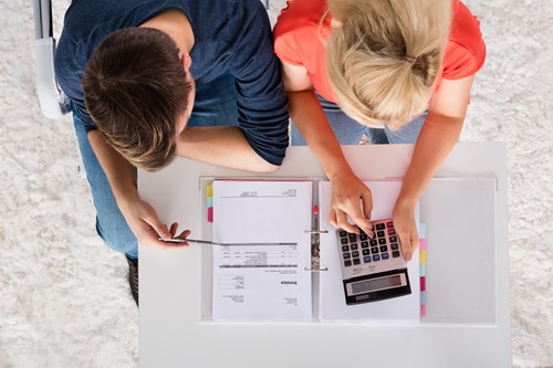 Two adults using calculator to work out bills