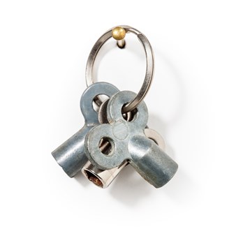 Three silver metal radiator bleed keys on a keyring hanging from a gold wall hook